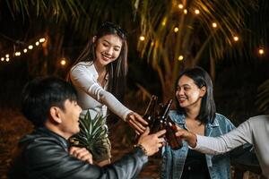 ritratto di contento asiatico amici avendo cena festa insieme - giovane persone seduta a bar tavolo tostatura birra bicchieri cena all'aperto - le persone, cibo, bevanda stile di vita, nuovo anno celebrazione concetto. foto