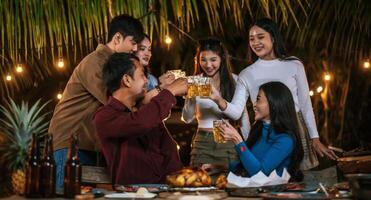 ritratto di contento asiatico amici avendo cena festa insieme - giovane persone tostatura birra bicchieri cena all'aperto - le persone, cibo, bevanda stile di vita, nuovo anno celebrazione concetto. foto