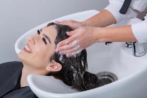 professionale parrucchiere lavaggio capelli di giovane donna nel bellezza salone. vicino su di donna di capelli nel bellezza salone, acconciatura concetto foto