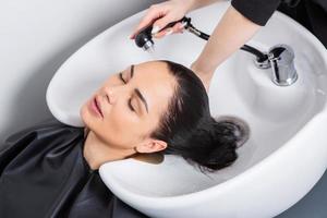 professionale parrucchiere lavaggio capelli di giovane donna nel bellezza salone.. vicino su di donna di capelli nel bellezza salone, acconciatura concetto foto