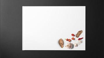 zenzero, aglio, peperoncino, peperoncini rossi e pepe nero su carta bianca su sfondo nero