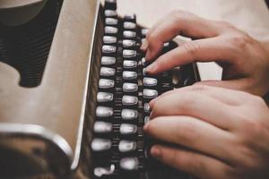 mani che digitano sulla macchina da scrivere vintage sul tavolo di legno foto