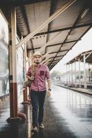 uomo giovane hipster che cammina attraverso la stazione ferroviaria foto