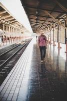 uomo giovane hipster che cammina attraverso la stazione ferroviaria foto