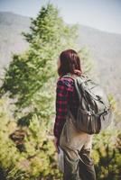 donna giovane viaggiatore con zaino in piedi su una montagna foto