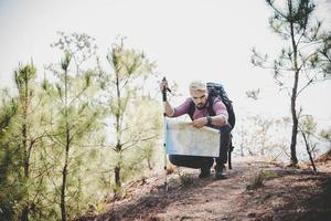 escursionista con mappa e grande zaino da viaggio in viaggio verso la montagna foto