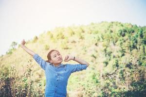 giovane donna in piedi a guardare il cielo con le mani alzate foto