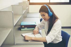 giovane studente asiatico che legge in biblioteca foto