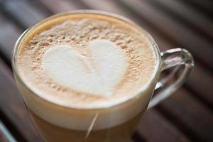 primo piano della tazza del cappuccino con il modello del latte a forma di cuore al caffè foto