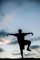 silhouette di giovane uomo che fa yoga al tramonto foto