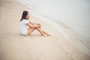 giovane donna seduta sulla spiaggia foto