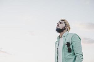 uomo giovane hipster in piedi in un parco con il cielo foto