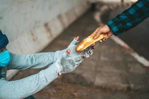 la macchina per il pane dà a un mendicante sul ciglio della strada foto