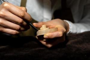 giovane Cinese femmina violino creatore Lavorando con sgorbia per fabbricazione un' nuovo violino foto