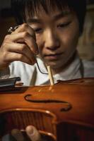 giovane Cinese violino creatore a opera nel sua laboratorio foto