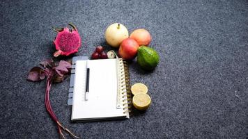 superiore Visualizza di salutare frutta e verdure con libro su buio sfondo. dieta salutare cibo concetto foto