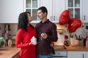 uomo e donna nel amore Data a casa nel cucina con chiavi di Casa. San Valentino giorno, contento coppia, amore storia. amore nido, mutuo, trasloco, Acquista, vero proprietà, alloggiamento per giovane famiglia foto