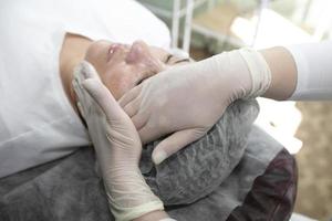 avvicinamento di un' estetista medico mano fare un' facciale pelle ringiovanimento medico procedura per un' donna. foto