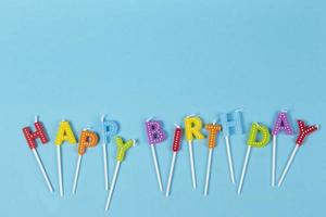 colorato candele nel lettere con contento compleanno lettering isolato su blu sfondo foto