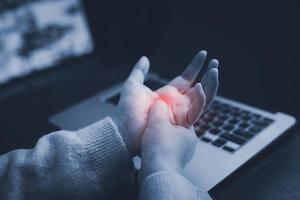 ufficio sindrome con mano dolore di professionale patologia, donna Tenere sua mano dolore a partire dal utilizzando il computer portatile o smartphone lungo tempo, salute cura e medico concetto, polso dolore. foto