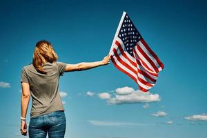 donna detiene Stati Uniti d'America bandiera contro blu cielo foto