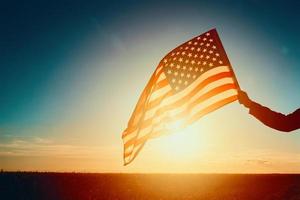 agitando Stati Uniti d'America bandiera nel mano a tramonto foto