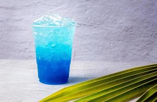 blu hawaiano bevanda nel un' plastica bicchiere e Noce di cocco le foglie. foto