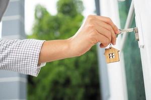 il femmina mano è utilizzando il chiave per Aperto il suo proprio Casa. nuovo casa, casa e proprietà di abitazione concetto foto