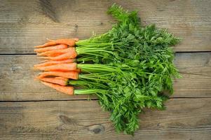 carota su di legno tavolo sfondo, fresco e dolce carote per cucinando cibo frutta e verdure per Salute concetto, bambino carote mazzo e foglia foto