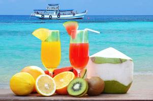estate succo bicchiere salutare Alimenti molti maturo frutta misto su il spiaggia blu mare foto