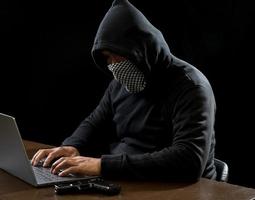 pirata spiare uomo uno persona nel nero felpa con cappuccio seduta su un' tavolo guardare computer il computer portatile Usato accesso parola d'ordine attacco sicurezza per circolare dati digitale nel Internet Rete sistema, notte buio sfondo. foto