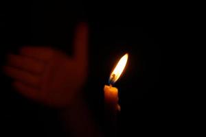 umano mani proteggere lume di candela a notte quello si illumina le cose. foto