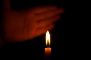 umano mani proteggere lume di candela a notte quello si illumina le cose. foto