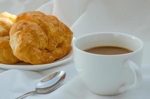 burro brioche e un' tazza di caffè per prima colazione foto