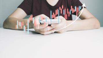 l'investitore sta negoziando azioni con lo smartphone, il trader analizza il prezzo delle azioni con il grafico a candele, la crescita del business, il cambio valuta, il progresso economico, la finanza con la tecnologia Internet. foto