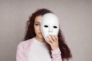 triste ragazza nascondiglio dietro a maschera foto