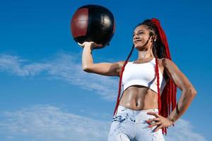 sfondo cielo. atletico donna con med sfera. forza e motivazione.foto di sportivo donna nel alla moda abbigliamento sportivo foto