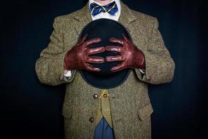 ritratto di uomo nel tweed completo da uomo e pelle guanti Tenere giocatore di bowling cappello su nero sfondo. classico e eccentrico inglese signore. foto