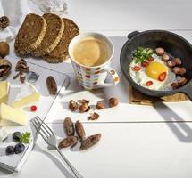 il giro Camembert formaggio, pezzi di affumicato salsiccia e un' il giro nero ghisa frittura padella con un' fritte pollo uovo foto