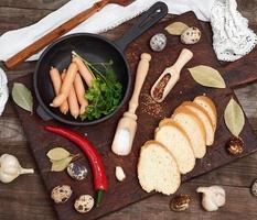 salsicce nel un' nero il giro ghisa frittura padella e crudo Quaglia uova foto