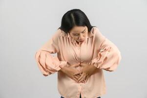 ritratto di giovane asiatico donna nel rosa camicia stomaco dolore isolato su bianca sfondo foto