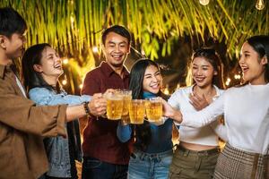 ritratto di contento asiatico amici avendo cena festa insieme - giovane persone tostatura birra bicchieri cena all'aperto - le persone, cibo, bevanda stile di vita, nuovo anno celebrazione concetto. foto