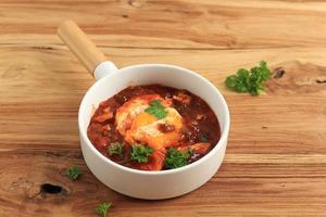 Shakshoka, fatti in casa uovo piatto con pomodoro salsa foto