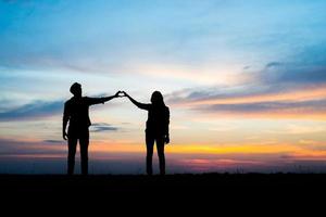 silhouette di una giovane coppia insieme durante il tramonto foto