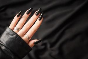 mani di un' giovane ragazza con nero manicure su Chiodi foto