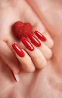 ragazze mani con rosso manicure e decoratina cuore foto