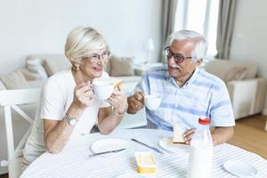 anziano coppia fabbricazione panini per prima colazione. contento vecchio coppia comunicare mentre godendo nel loro prima colazione. anziano coppia avendo divertimento. foto