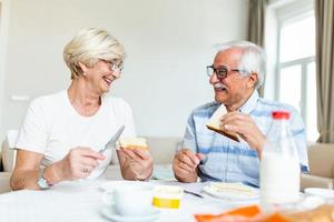 anziano coppia fabbricazione panini per prima colazione. contento vecchio coppia comunicare mentre godendo nel loro prima colazione. anziano coppia avendo divertimento. foto