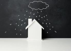 di legno Casa e un' disegnato nube con pioggia con bianca gesso su un' nero gesso tavola. vero tenuta assicurazione concetto foto