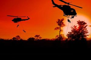 silhouette soldati rappel giù per attacco a partire dal elicottero con tramonto e copia spazio Inserisci testo foto